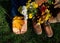 bare feet of child lying on grass, next to brown shoes, bouquet of chrysanthemums and leaves on sunny autumn day