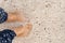 Bare feet of a girl on the sea sand with shells. Top view