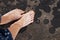 Bare feet of a girl with the stuck sand. Top view