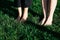 Bare feet of young girls stand barefoot in the dense green grass