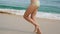 Bare feet of young woman jogs over wet sand in shallow waterline. Female legs runs along seashore. Girl spends time near