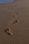 Bare footprints on beach disappearing into distance