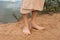 Bare male feet on the sand against the background of the pond