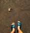 Bare male legs in blue slippers on the asphalt ground. Autumn leaf