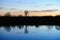 Bare trees reflected in a still river at sunset