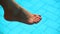 Bare woman feet over swimming pool water