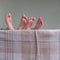 Barefeet of children in wooden bed covered with blanket.