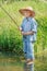 Barefoot angler boy fishing standing in transparent freshwater pond