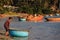 Barefoot Asian Man Pushes Blue Round Boat on Water from Beach