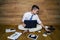 A barefoot businessman sitting on the floor against a wall and using laptop