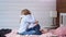 Barefoot child girl gives big hug to her mother sitting on bed in bedroom at home interior full shot