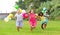 Barefoot children with balloons running through grass