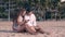 Barefoot couple sits on sand and girl types on smartphone
