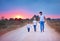 Barefoot father and sons walking together along a countryside summer road at sunset. happy family
