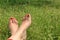 Barefoot female feet on green field