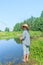 Barefoot fishing boy standing in transparent yellowish waterbody