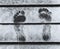 Barefoot footprints close up on wooden jetty with clear white snow in winter