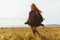 barefoot girl in ethnic cape runs on the steppe grass with fluttering hair