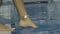 Barefoot girl moves her foot in clean blue water while standing at the edge of swimming pool. Female legs close up.