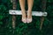 Barefoot girl in old rustic clothes is sitting on the ladder near wooden house. Summer day on farm barnyard. Stylish vintage