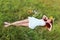 Barefoot girl in wreath lies on grass