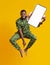 Barefoot happy black guy in African costume jumping up with smartphone over orange studio background, mockup