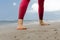 Barefoot legs of the athlete close-up. The woman is engaged in warm-up and yoga on the beach