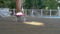 Barefoot legs of a little girl in pink shorts skating on a skateboard along the swimming pool