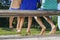 Barefoot legs of three kids sitting on the bench