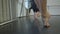 Barefoot legs of young Caucasian slim woman rehearsing at dance barre with unrecognizable friends training at background