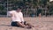 Barefoot man plays with sand on evening beach by ocean