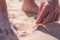 Barefoot man was walking along the beach and found a shard of broken glass from a bottle lying dangerously in the sand.