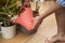 Barefoot man watering various houseplants in living room