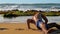 Barefoot muscular gymnast exercises on yellow wet sand