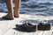 Barefoot person standing near dirty shoes on a dock by the sea