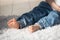 barefoot toddler boy in jeans sits on the floor on a high-pile white carpet