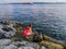 Barefoot tourist sits on the stones on the shore of Bosphorus against the background of a tanker in the water and the panorama of