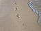 Barefoot walk marks on wet white sand. Beach view photo. Foot marks on beach.