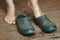 Barefoot woman puts rubber boots on standing on a wooden floor