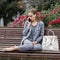 Barefoot woman sits on bench in park and communicates on a smartphone