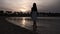 Barefoot woman spending sunset time at beach. Pretty girl walking at coastline.