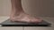 Barefoot woman steps on bathroom scales.