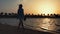 Barefoot woman walking along coastline. Pretty girl relaxing at sunset beach.