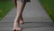 barefoot woman is walking over wooden path in park, closeup of feet