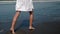 Barefoot woman is walking on wet sand seacoast