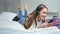 Barefoot young pretty girl lying on bed in bedroom listening music using headphones and smartphone