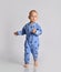 Barefooted baby boy in blue fleece jumpsuit with stars runs