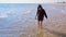 Barefooted child boy walks on the sand beach at sea cold water on vacation.