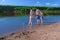 Barefooted family in swimsuits in river walking in water at Summer warm day.