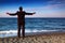 Barefooted man in suit stands back on stone coast